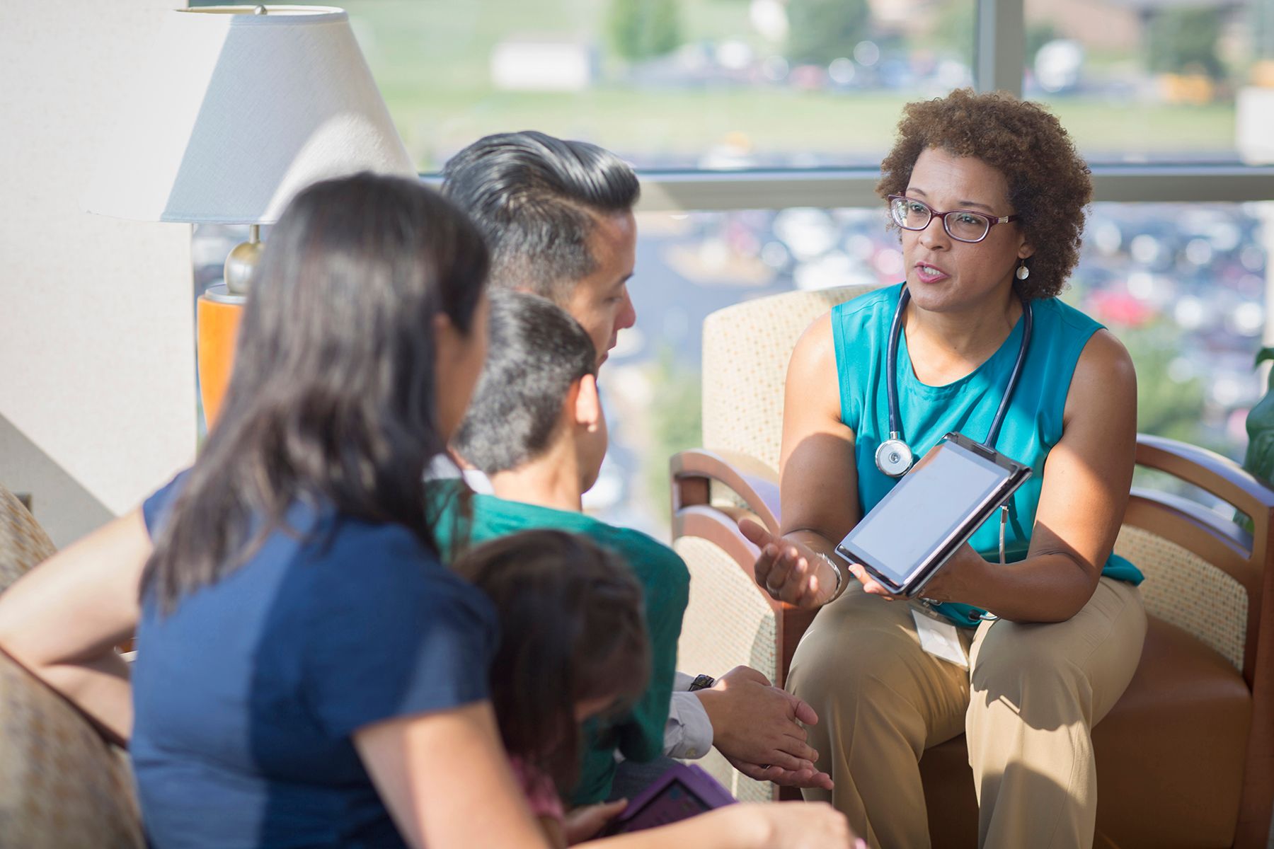Female doctor explaining something to a family and using a tablet as a teaching tool