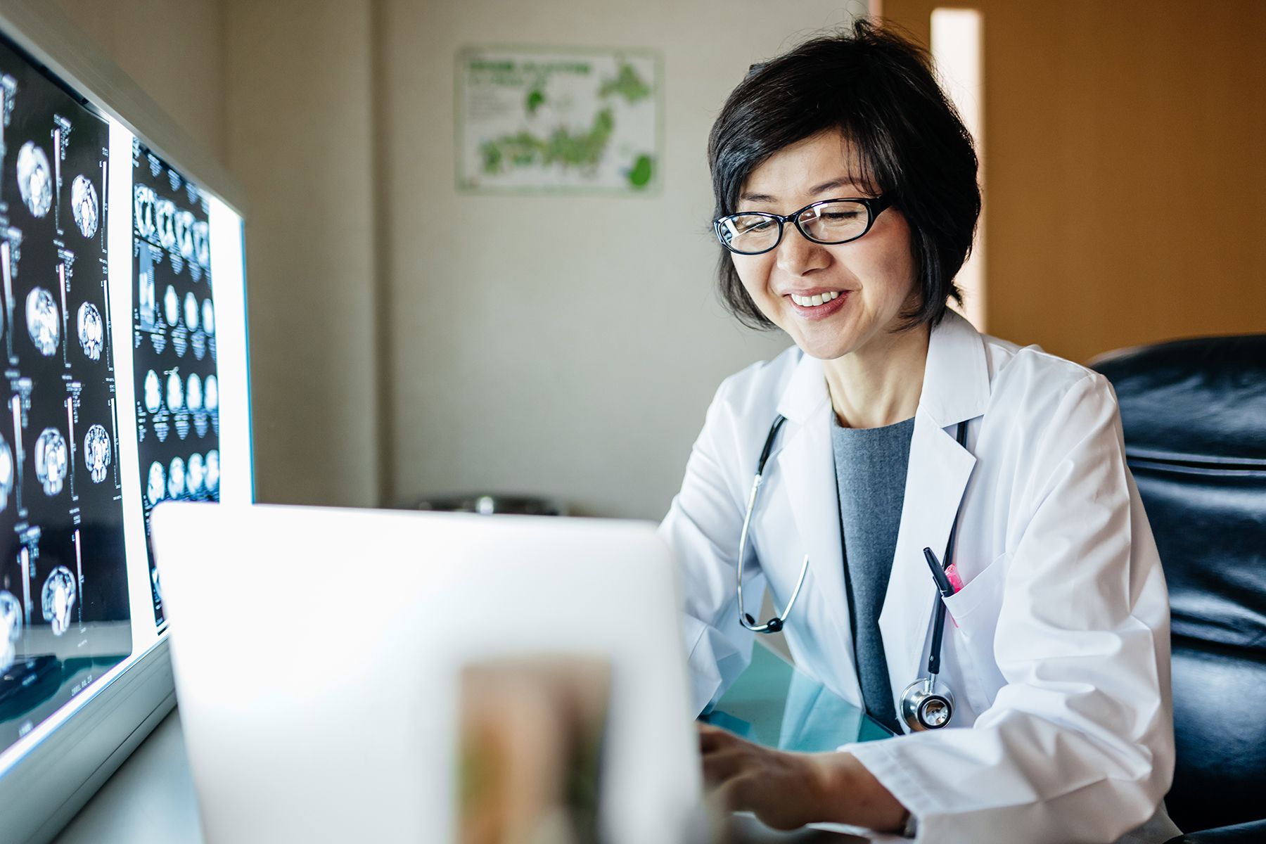 Female doctor smiling at a laptop next to x-rays